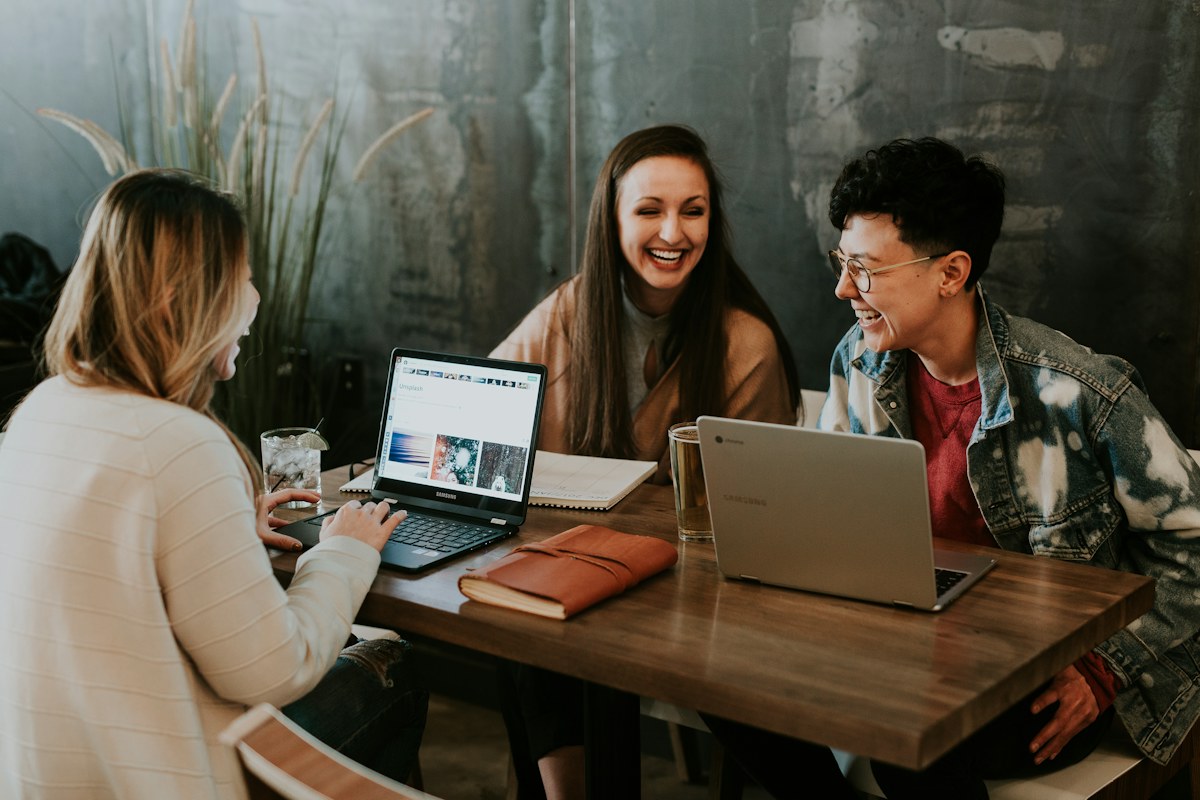 Colleagues smiling while working together at laptops
